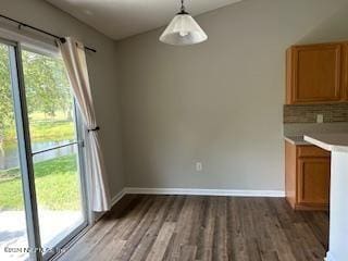 unfurnished dining area featuring baseboards and wood finished floors