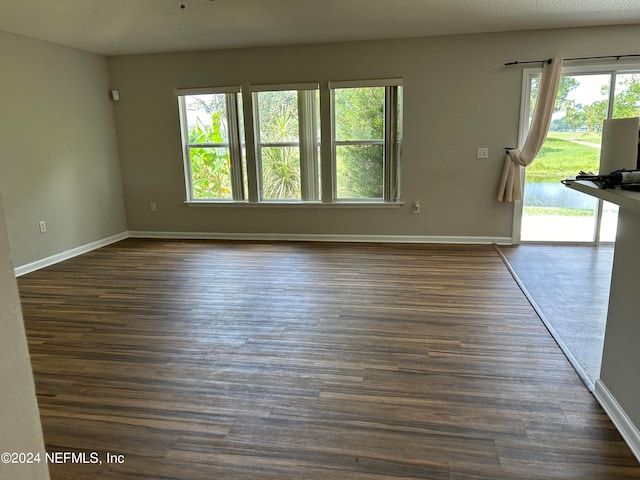 unfurnished living room with dark hardwood / wood-style flooring and a wealth of natural light