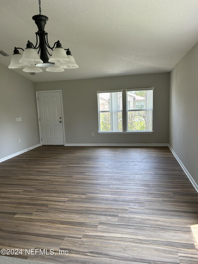 spare room with a notable chandelier, dark hardwood / wood-style floors, and a textured ceiling