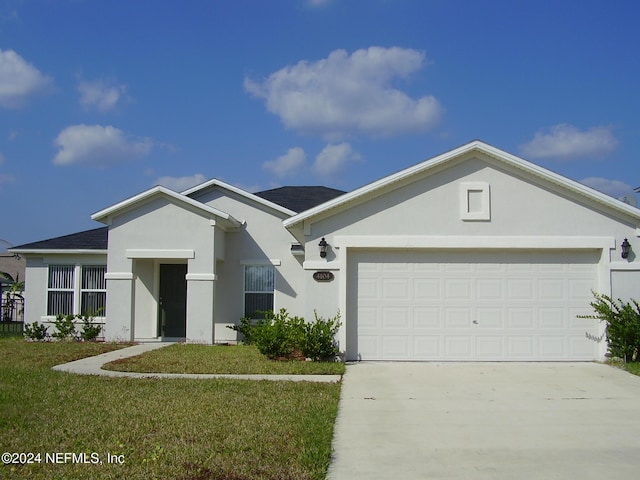 ranch-style house featuring a front yard, concrete driveway, an attached garage, and stucco siding