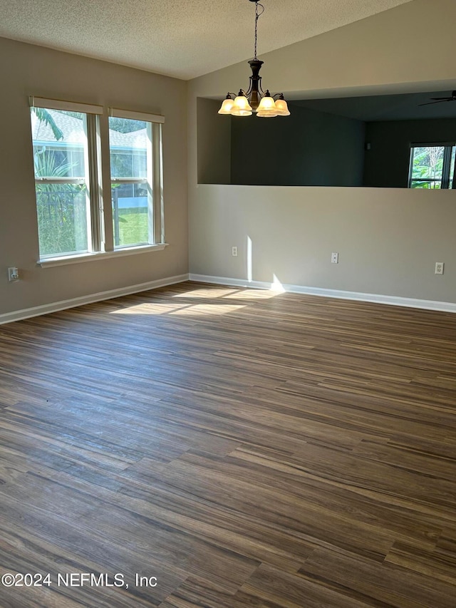 unfurnished room with a wealth of natural light, an inviting chandelier, a textured ceiling, and lofted ceiling