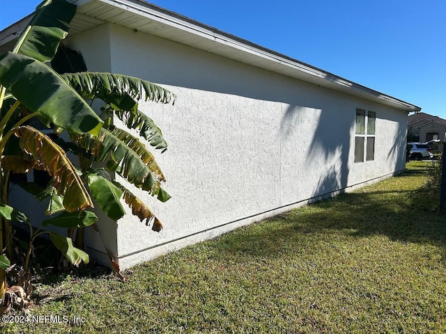 view of side of property with a lawn and stucco siding