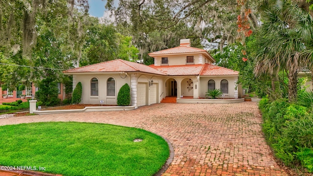 mediterranean / spanish-style house with a garage and a front yard