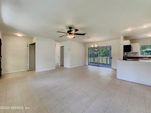 unfurnished living room featuring sink, ceiling fan with notable chandelier, and light tile patterned floors