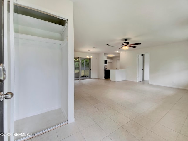 interior space with ceiling fan with notable chandelier and light tile patterned floors