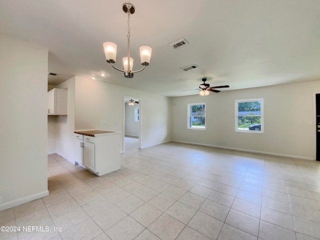 tiled empty room featuring ceiling fan with notable chandelier