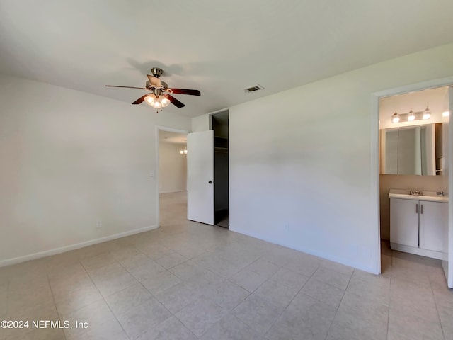 unfurnished bedroom with ceiling fan, ensuite bathroom, sink, and light tile patterned floors