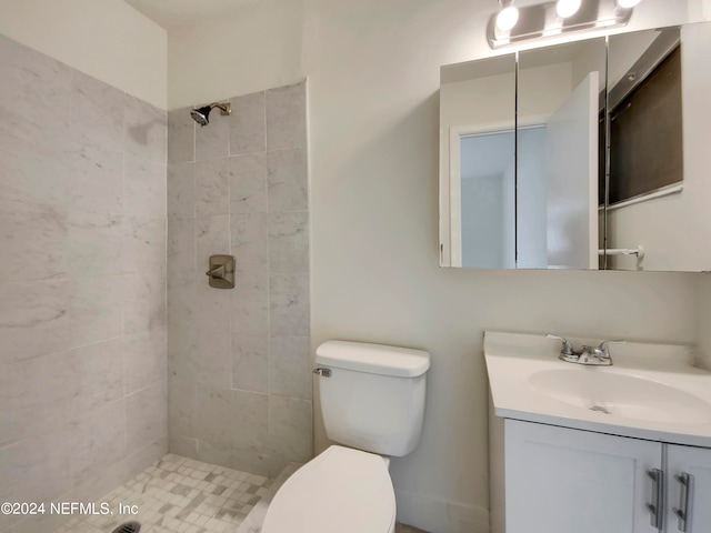 bathroom featuring vanity, a tile shower, and toilet