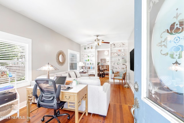 living room with ceiling fan, built in features, and hardwood / wood-style flooring