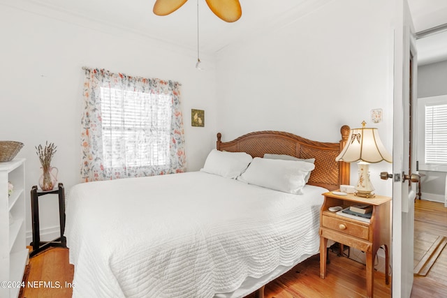 bedroom featuring multiple windows, ornamental molding, ceiling fan, and hardwood / wood-style flooring