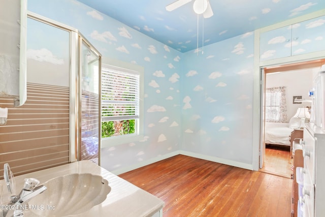 bathroom featuring a ceiling fan, a sink, wood-type flooring, ensuite bath, and baseboards