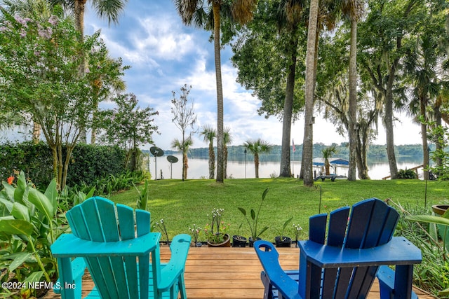 wooden terrace with a water view and a yard