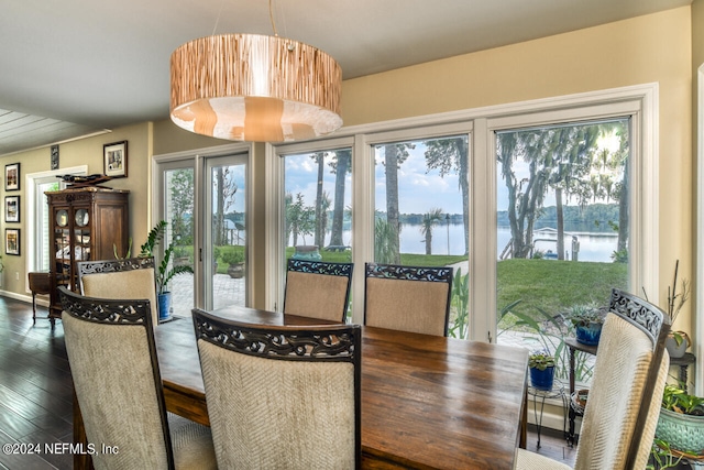 dining area with hardwood / wood-style flooring and a water view