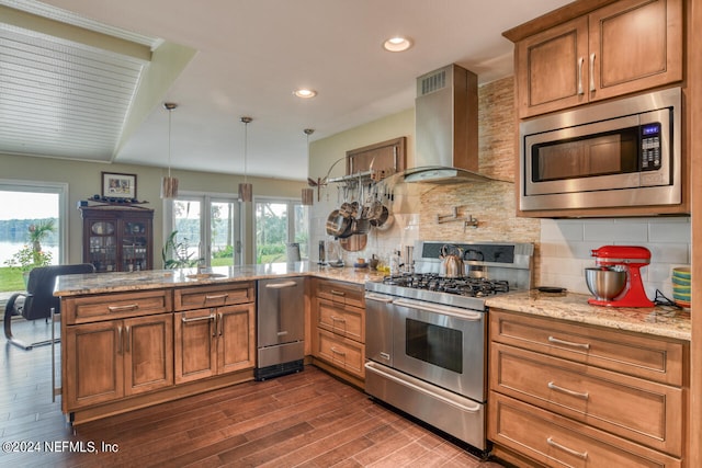 kitchen featuring stainless steel appliances, decorative backsplash, wall chimney exhaust hood, kitchen peninsula, and dark wood-type flooring