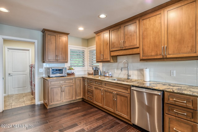 kitchen with dishwasher, decorative backsplash, sink, light stone counters, and dark hardwood / wood-style flooring