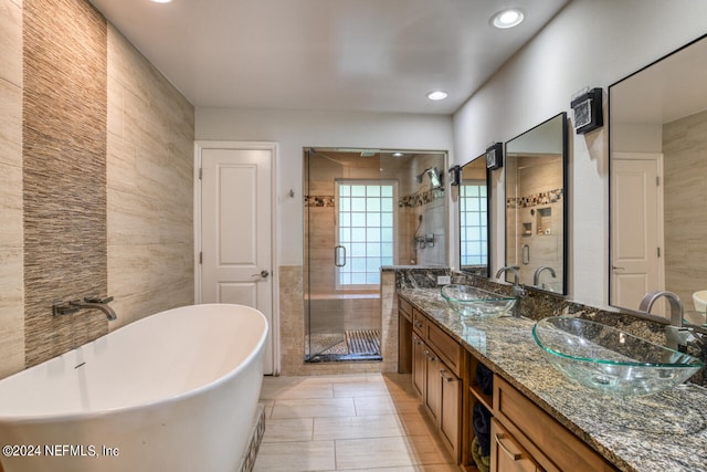 bathroom with tile walls, double vanity, separate shower and tub, and tile patterned floors