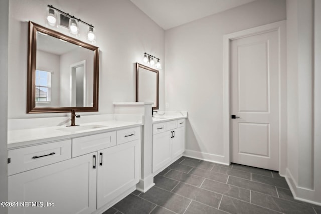 full bathroom with two vanities, a sink, baseboards, and tile patterned floors