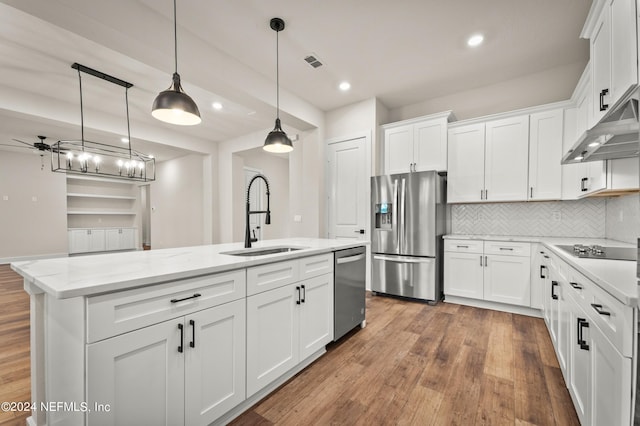 kitchen with stainless steel appliances, visible vents, white cabinetry, a sink, and wood finished floors