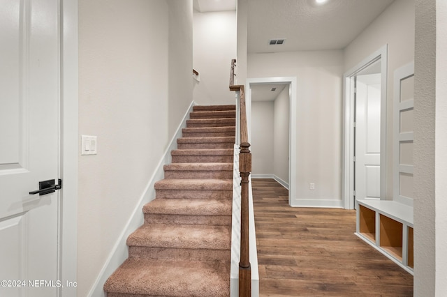 stairs featuring wood finished floors, visible vents, and baseboards