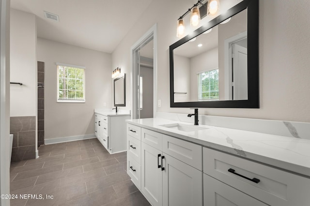 full bathroom featuring two vanities, a sink, visible vents, and baseboards