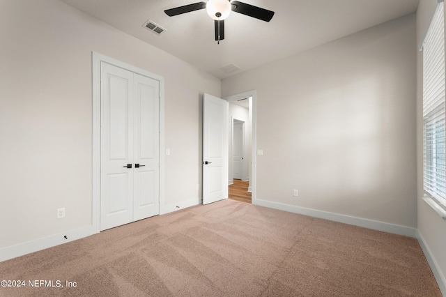 unfurnished bedroom with light colored carpet, a ceiling fan, baseboards, visible vents, and a closet