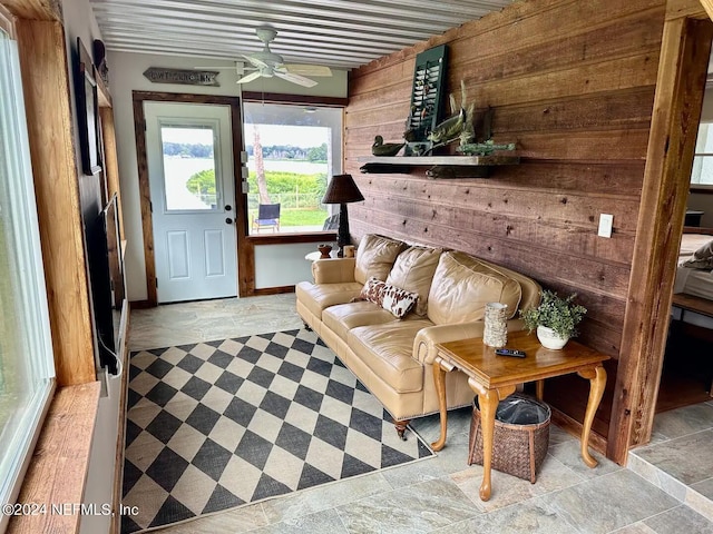 interior space with ceiling fan, wooden walls, and light tile patterned flooring