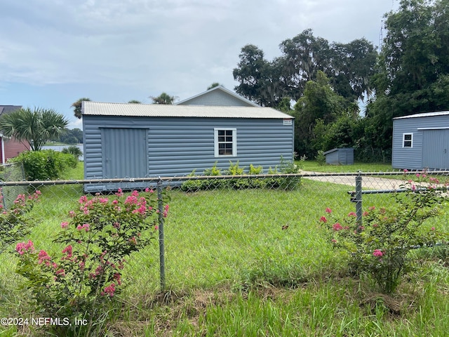 rear view of house with a shed and a lawn