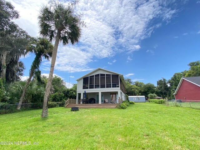 back of property with a yard, a deck, and a sunroom