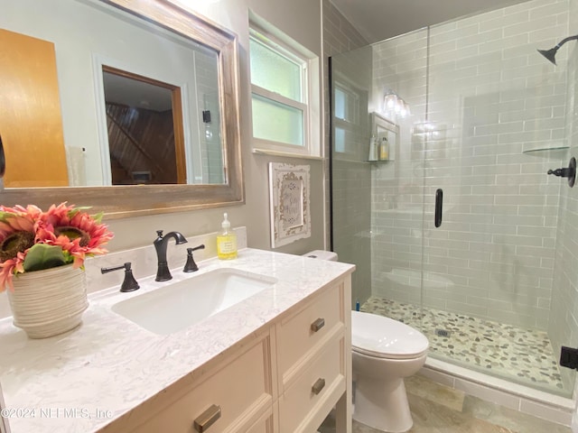 bathroom with a shower with shower door, toilet, vanity, and tile patterned floors