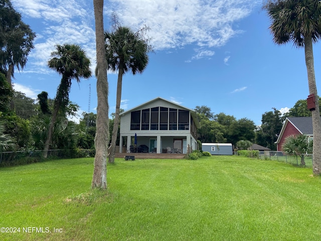 rear view of house featuring a sunroom and a lawn