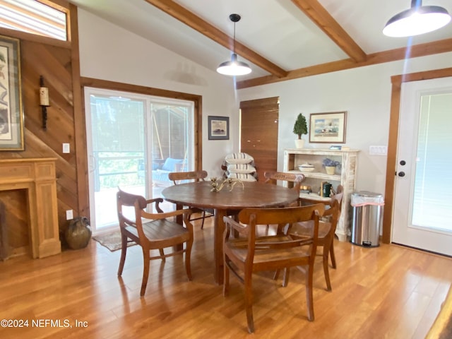 dining room featuring wooden walls, light hardwood / wood-style floors, and lofted ceiling with beams