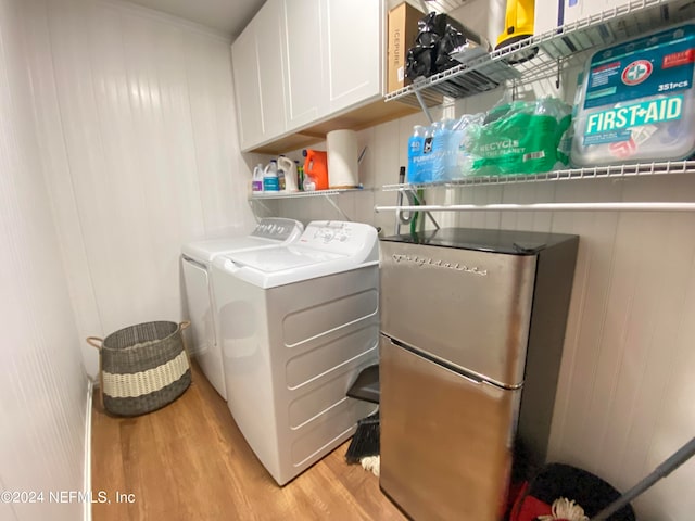 laundry area featuring light wood-type flooring, washing machine and clothes dryer, and cabinets