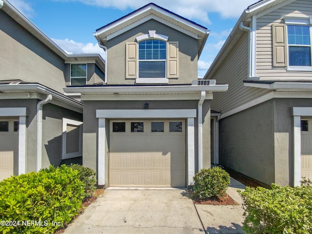 view of front of property featuring a garage, concrete driveway, and stucco siding