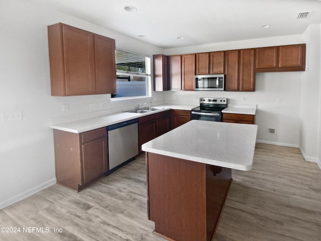 kitchen featuring a breakfast bar, sink, appliances with stainless steel finishes, light hardwood / wood-style floors, and a kitchen island