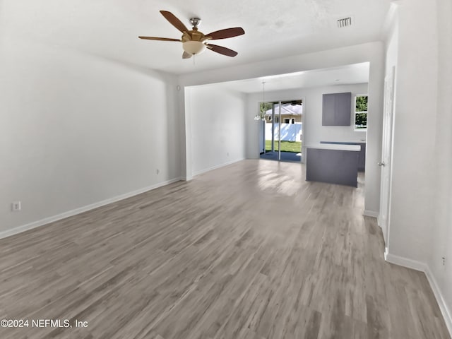 unfurnished living room featuring baseboards, visible vents, a ceiling fan, and light wood-style floors