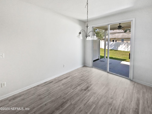 unfurnished dining area featuring an inviting chandelier, wood finished floors, and baseboards