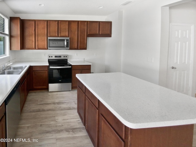 kitchen featuring visible vents, a kitchen island, stainless steel appliances, light wood-type flooring, and a sink