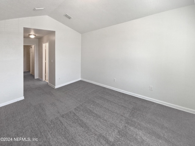 unfurnished room featuring lofted ceiling, baseboards, visible vents, and dark colored carpet