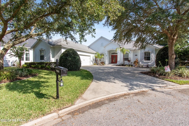 ranch-style home with a garage, driveway, a front yard, and stucco siding