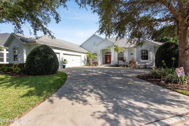 ranch-style house with driveway, a front lawn, an attached garage, and stucco siding