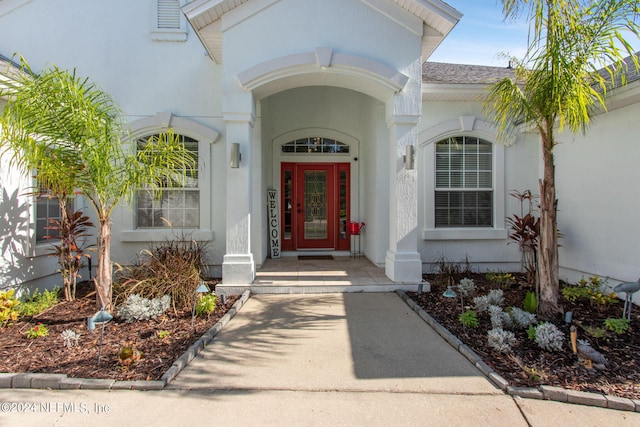 property entrance with roof with shingles and stucco siding