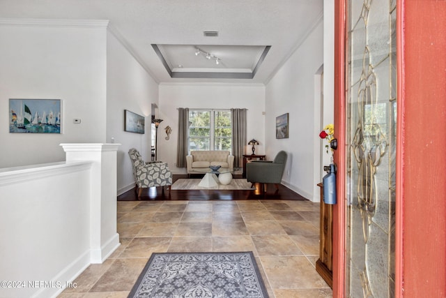 foyer featuring rail lighting, visible vents, baseboards, and a raised ceiling