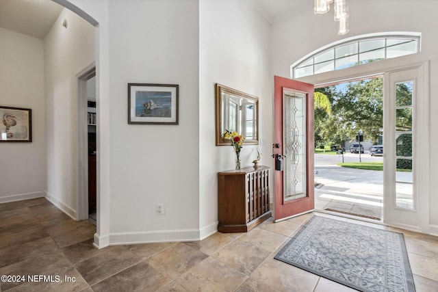 entrance foyer featuring baseboards, arched walkways, and a notable chandelier