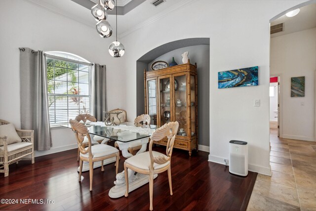 dining area with arched walkways, crown molding, baseboards, and wood finished floors