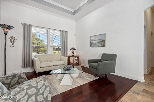 living area with arched walkways, a tray ceiling, crown molding, and baseboards