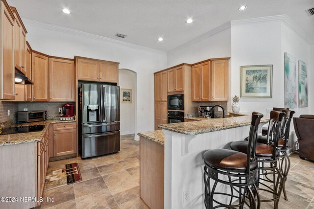 kitchen featuring kitchen peninsula, light stone counters, light tile patterned flooring, and black appliances