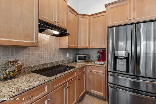 kitchen with black electric stovetop, under cabinet range hood, stainless steel refrigerator with ice dispenser, backsplash, and light stone countertops