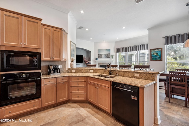 kitchen with brown cabinets, a sink, light stone countertops, a peninsula, and black appliances