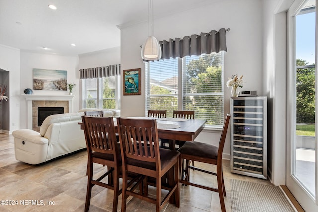 dining space with baseboards, wine cooler, crown molding, a fireplace, and recessed lighting