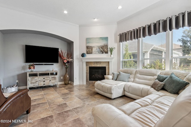 living area featuring baseboards, recessed lighting, a tiled fireplace, and crown molding